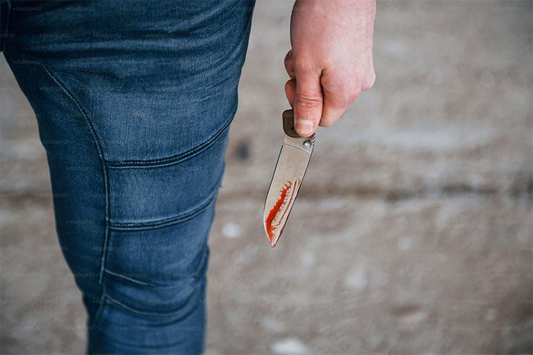 A man in jeans holding a knife