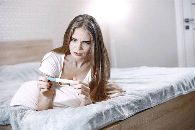 Amazed woman looking at pregnancy test