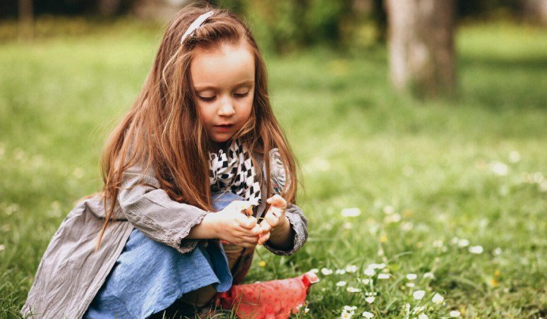 Little girl on a park are curious what are the odds of finding a four leaf clover