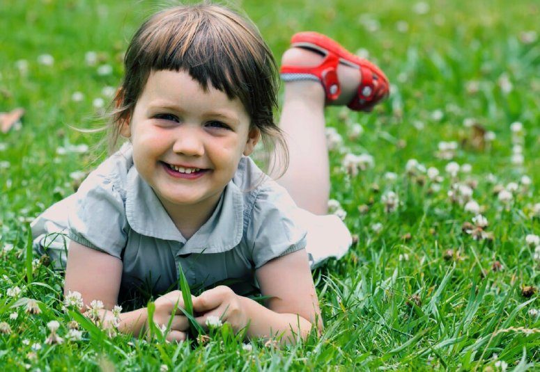 Little girl smiling while searching for four leaf clover