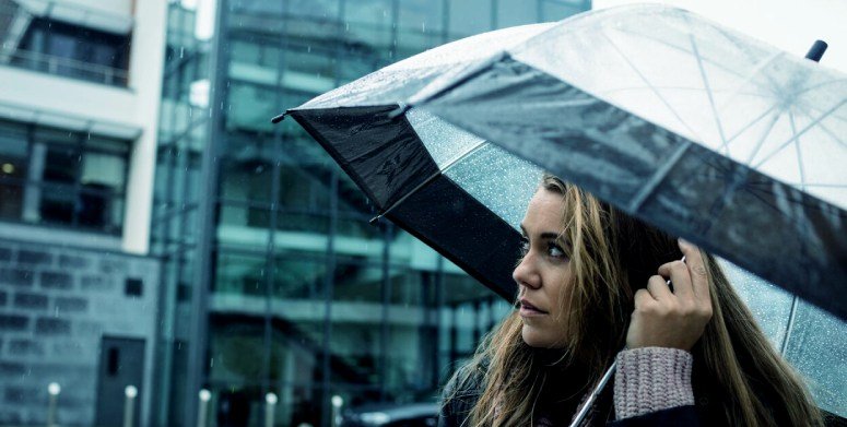 A woman holding an umbrella is wondering what are the chances of getting struck by lightning