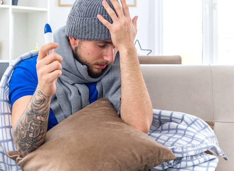 A very depressed man holding a pillow with one hand and his head with the other