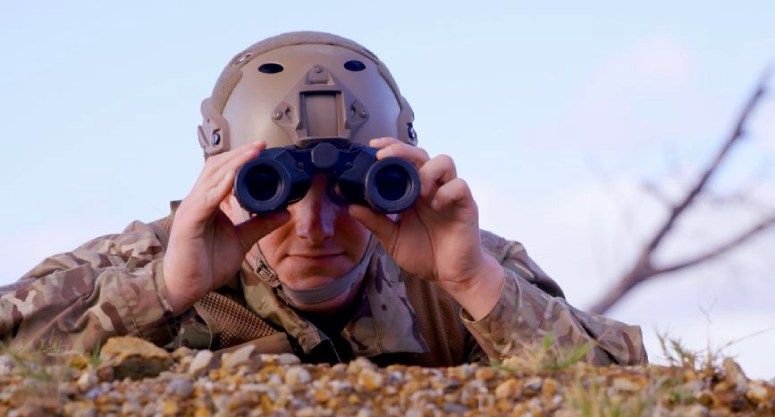 A soldier looks through binoculars