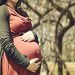 Pregnant woman holding her stomach in the nature