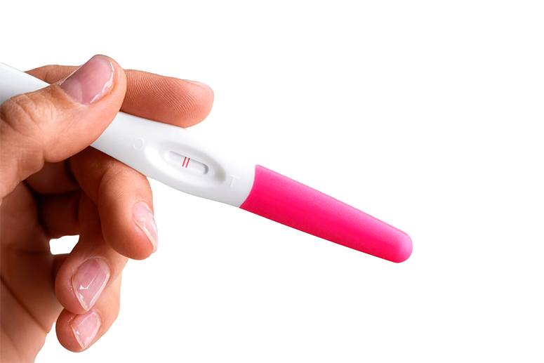 Hand holding positive pregnancy test