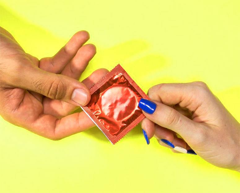 2 hands holding a condom