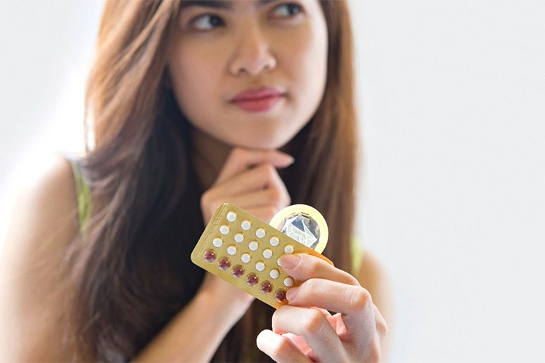 Girl holding condom and pills