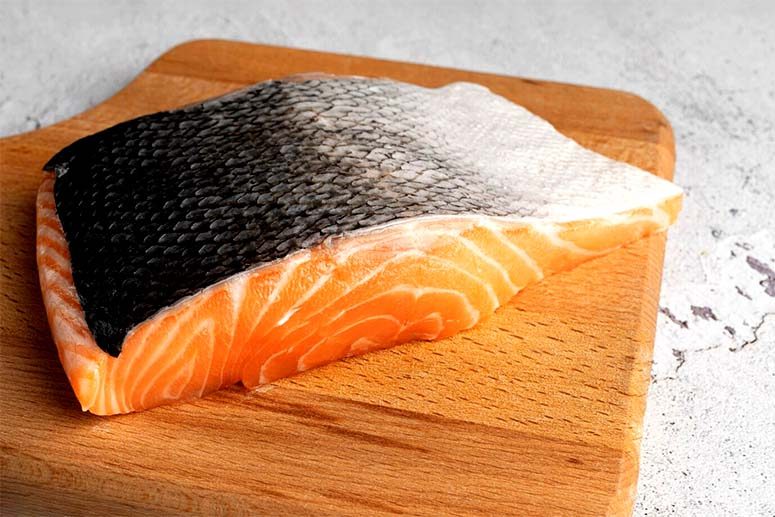 A large piece of salmon on a wooden board