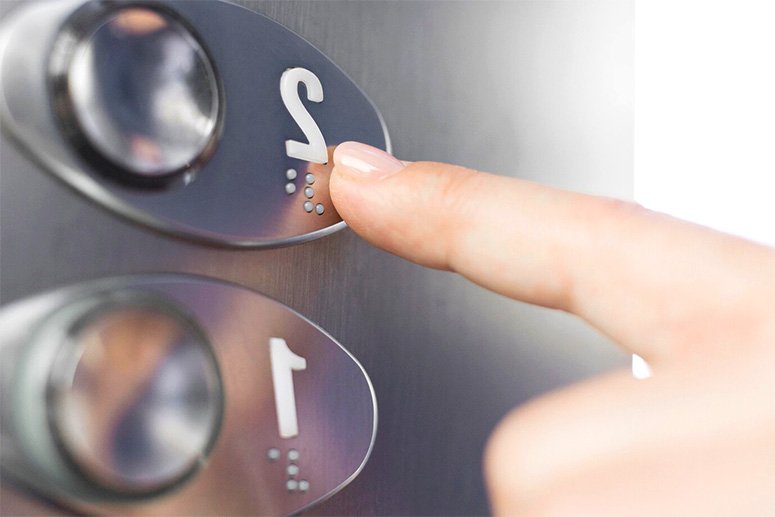 A finger pins a button for a floor in an elevator