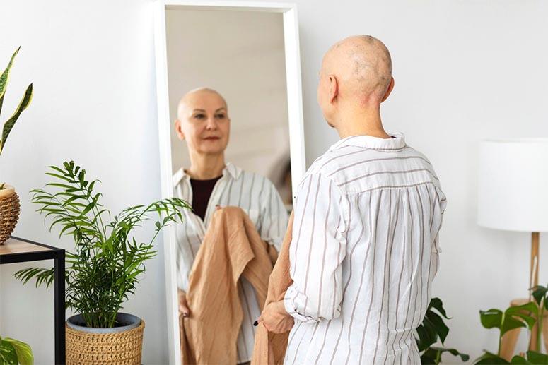 A woman with cancer looks in the mirror