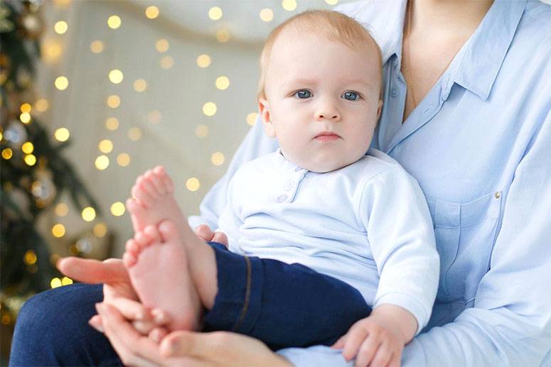 A baby boy held by her mom