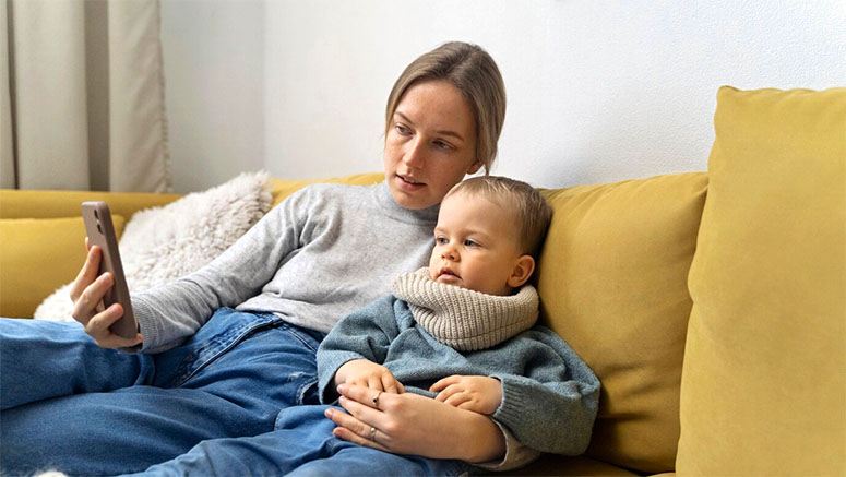 Mom shows something in the phone to her baby