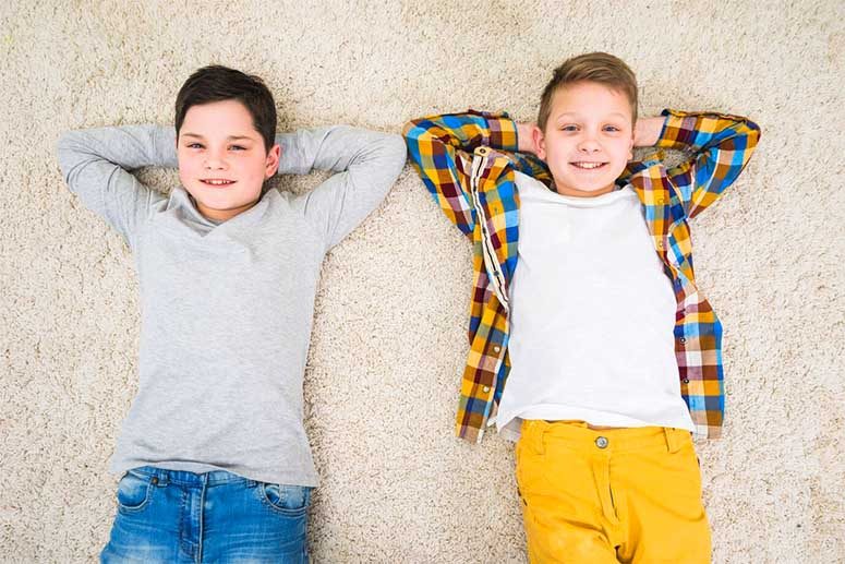 Two boys who are fraternal twins lying on the ground