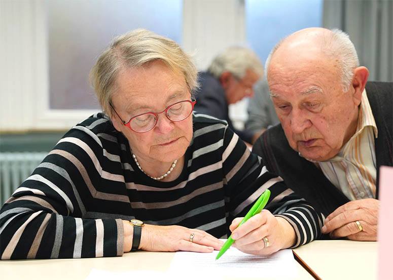 An old woman signs a marriage contract while the man watches her