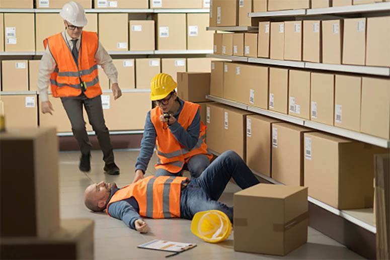 A construction worker makes a phone call after realizing that his colleague has passed out