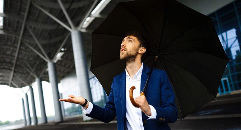 Amazed man holding an umbrella checks if it's raining